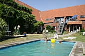 View of people in swimming pool and garden in hotel