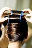 Rear view of woman putting large curlers in hair