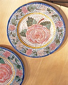 Colourful mosaic plate with rose pattern on wood