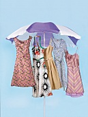 Sommerkleider hängen unter einem Sonnenschirm