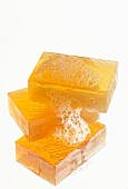 Three orange soaps with foam stacked on white background