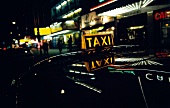 Taxi at night in entertainment district of city with colourful lights
