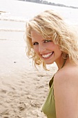 Portrait of beautiful blonde woman wearing green halter top, smiling