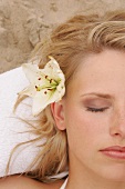Close-up of pretty blonde woman with flower in her hair, eyes closed
