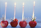 Mehrere Äpfel als Kerzenhalter, verziert mit Beeren und Gespenstergras