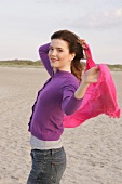 Frau mit rosa Schal am Strand