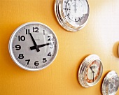 Close-up of various round wall clocks on yellow wall