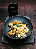 Gnocchi garnished with sage and parmesan cheese in bowl