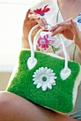 Close-up of woman holding green plush handbag with white blossom
