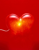 Close-up of illuminated red heart shaped lamp on red background