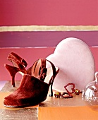 Close-up of wine red velvet pumps, altrosane heart shaped box and earrings
