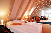 View of room with bed, cushions, orange chairs and illuminated lamp at hotel in Germany