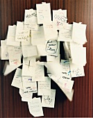 Several sticky notes with written texts hanging on dark wood