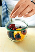 Pfirsich, Kirschen und andere Früchte werden in ein  Einmachglas gelegt