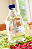 Close-up of sample liquid in bottle with label on floral pattern tablecloth