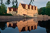 Schlosshotel Münchhausen spiegelt sich in der Abendsonne im Teich