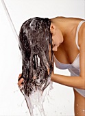 Woman in lingerie washing her hair while standing under shower 