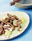 Close-up of beef with grapes and cashews on plate