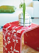 Close-up of red side table with white floral pattern motif