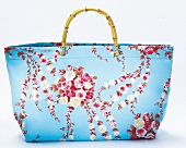 Hellblaue Strandtasche mit Blumenmuster.