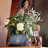 Close-up of perfume bottle kept beside flower vase