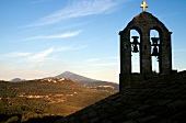 View of old stone church bells with mountain and sky in background
