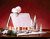 Gingerbread with pine trees and snow in the form of illuminated witch house for Christmas
