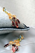 Close-up of pair of earrings with gemstones on cashmere pillow