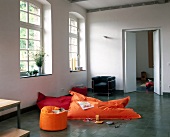 Living room with white walls, tiled floor and orange pillows by window