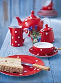 Red polka dotted cup and teapot with toast on saucer