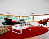 Wohnzimmer mit Ledersofa und rotem rundem Teppich