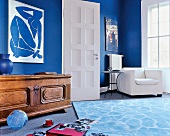 Wohnzimmer mit blauen Wänden, Sessel und rustikalen Holztruhe.