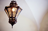 Orientalische Lampe hängt in einem Rundbogen von der Decke.