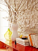 Willow twigs in vase on red wall cabinet against stone wall