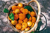 Orangen z. T. mit Blättern im Korb auf Boden, Aufnahme von oben