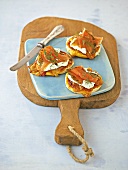 Mini-pizzas and gravlax with knife on chopping board