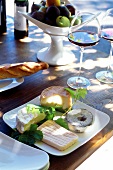 Various types of cheese on plate with bread and wine glass on table