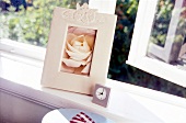 Wooden photo frame and alarm clock on window sill
