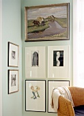 Verschiedene Bilder an der Wand, davor ein Korbstuhl.