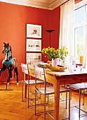 Essplatz im Zimmer in Rot: Holztisch + Stühle mit Geflecht, Karusselpferd