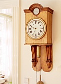 Wooden pendulum clock on the wall