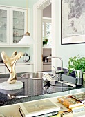 Detailaufnahme Küche: Runde Spüle, Arbeitaplatte grau, davor Bücher.