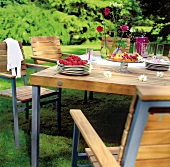 Holztisch gedeckt im Garten, mit Erdbeeren und Kuchen.