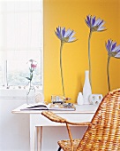 weisser Tisch vor gelber Wand mit aufgeklebten Blüten aus Papier