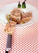Aspic pork with pieces and knife on plate