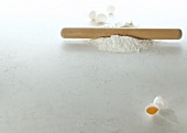 Rolling pin on flour and eggs on white background