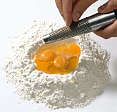Hand grating ingredient in egg yolks and corn flour, step 1