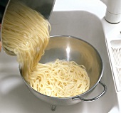 Boiled pasta being drained into casserole