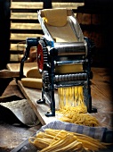 Pasta dough being cut in old pasta machine with cutting roller