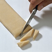 Hand cutting dough with knife for preparing maltagliati pasta, step 1